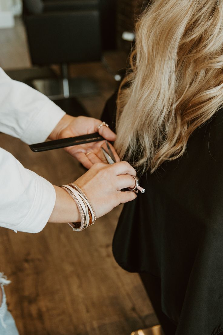 Mains d'une professionnelle coupant des cheveux blonds